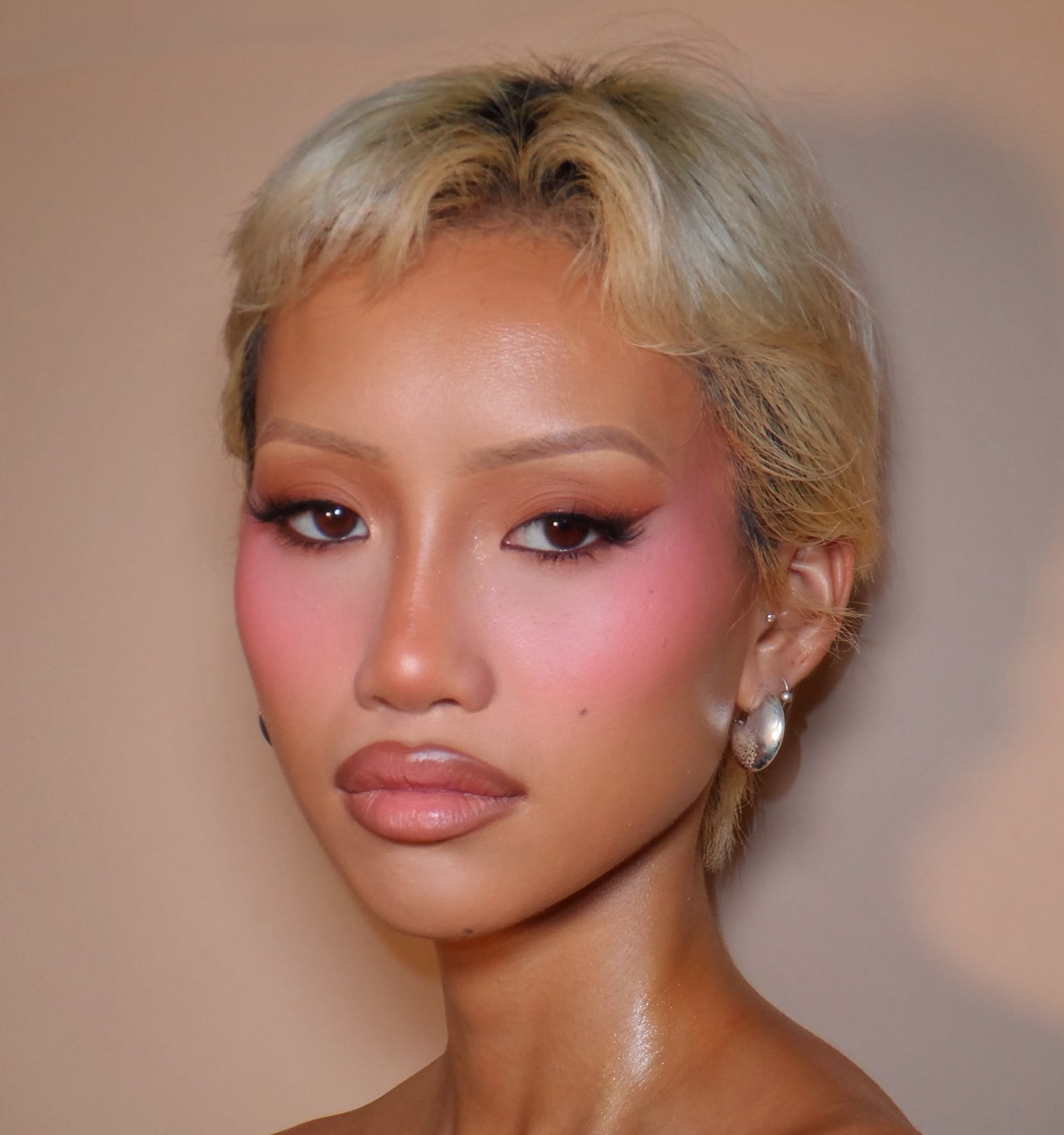 Soft glam with a blonde pixie cut and a warm pink blush